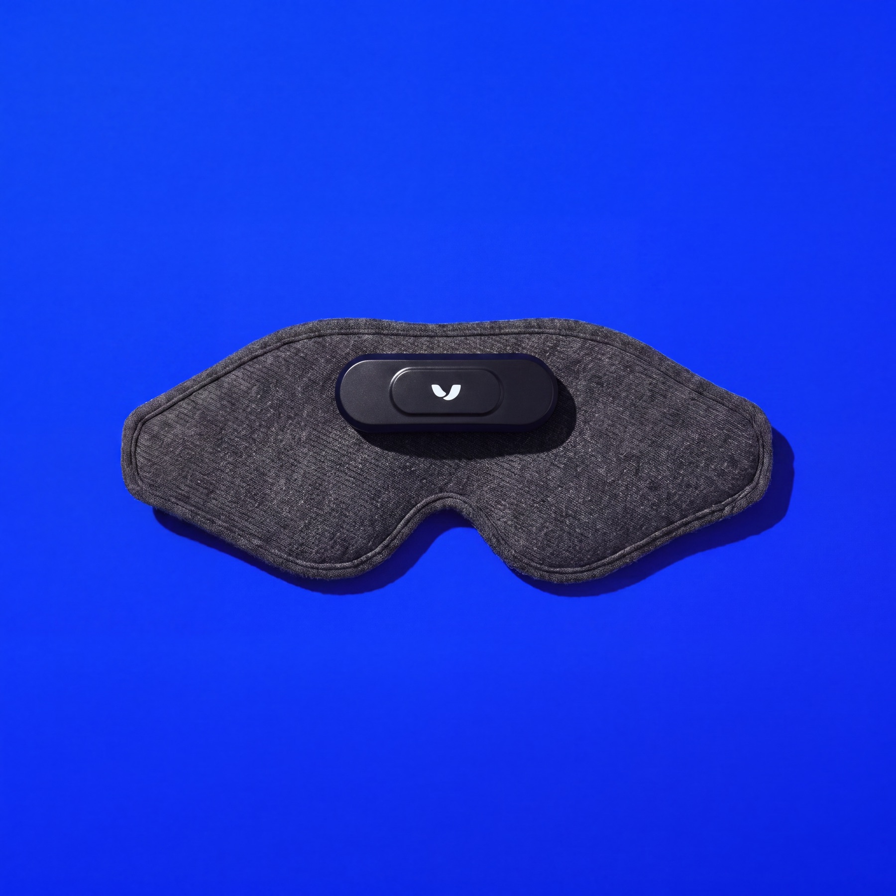 Overhead flat-lay of the Mask and its strap on a full electric-blue ground