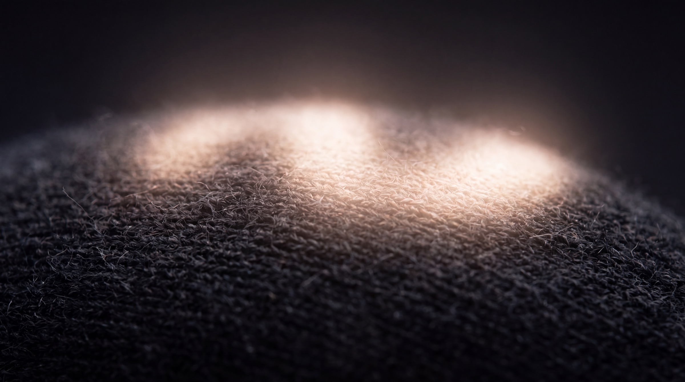 Extreme macro of light pulsing through the Mask’s charcoal knit weave