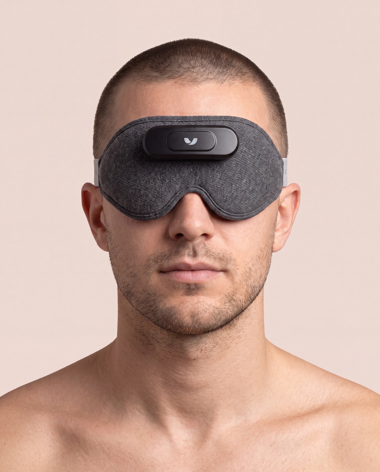 Bare-shouldered man wearing the Mask over his eyes, composed, in a warm bone-toned studio